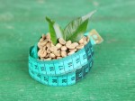 Raw green coffee beans and measuring tape, on color wooden background. Concept of weight loss