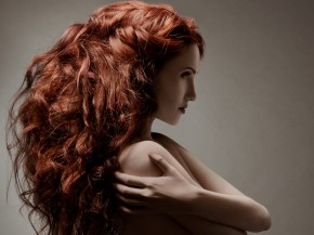 Beautiful woman with curly hairstyle against gray background