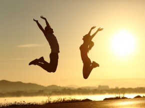 Fitness couple jumping happy at sunset