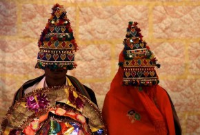 A bride and groom wearing traditional handmade garlands wait for their wedding to start during a mass marriage ceremony in Karachi