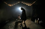 Girl does her homework as her mother makes corn tortillas for lunch in their adobe home on the outskirts of Chiquimula