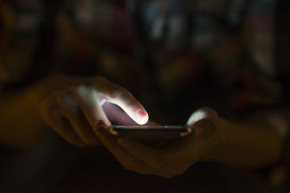 Woman using her mobile phone, city skyline night light backgroun